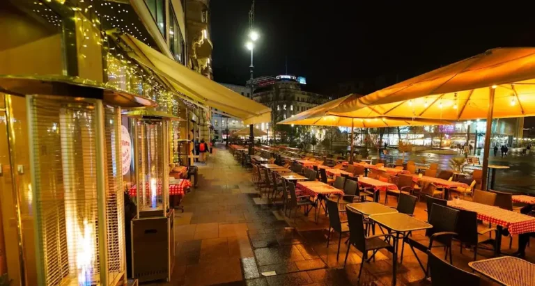 Old Mama's terrace in the evening, the lamps lit along the tables